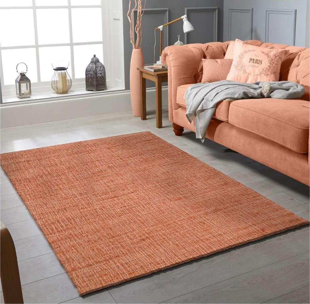 A solid kilim loom dhurrie in burnt orange laid in a living room