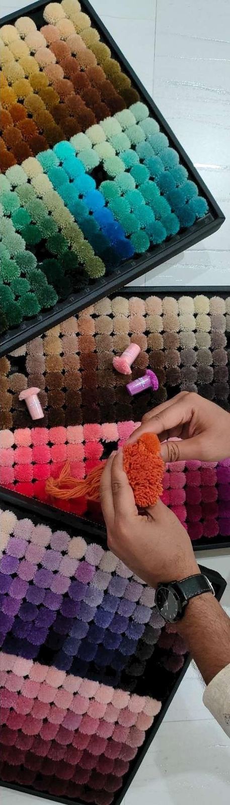 Trays of coloured wool pompoms used to match dye shades before production